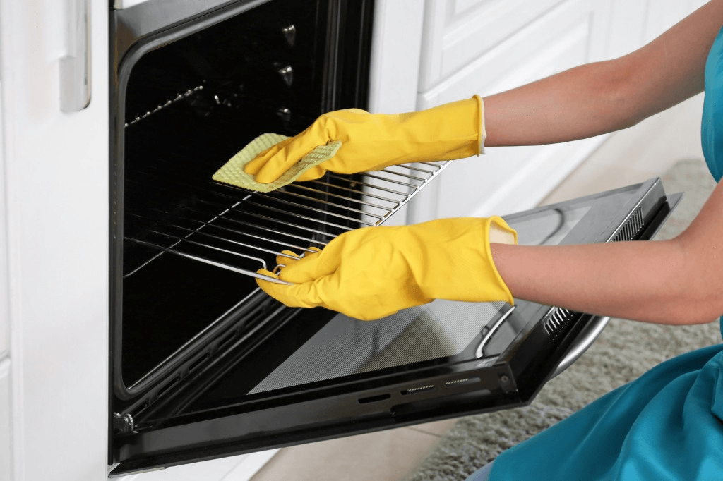 Gloved hands deep-cleaning the inside of an oven rack